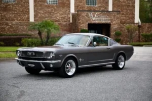 A rare view of a 1966 Mustang 2+2 Fastback parked in front of “Vickers Metal Works inc.”