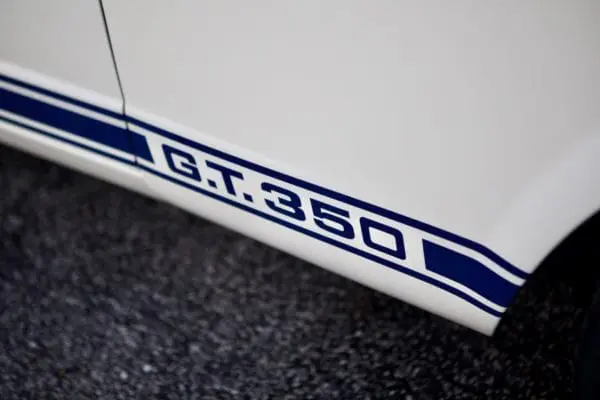 A close-up look of a white 1966 Shelby GT 350/ GT350H letter emblem.