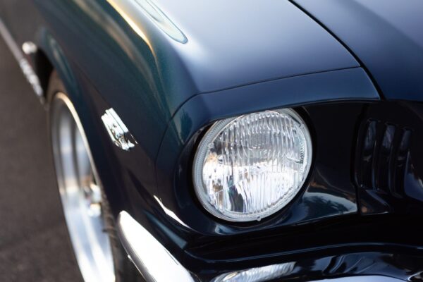 The front headlight of a black 1966 Mustang Convertible