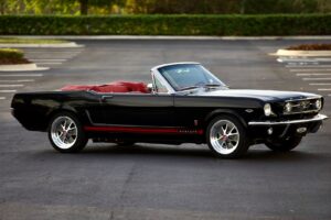 A rare view of a black 1966 Mustang Convertible parked in a parking lot.