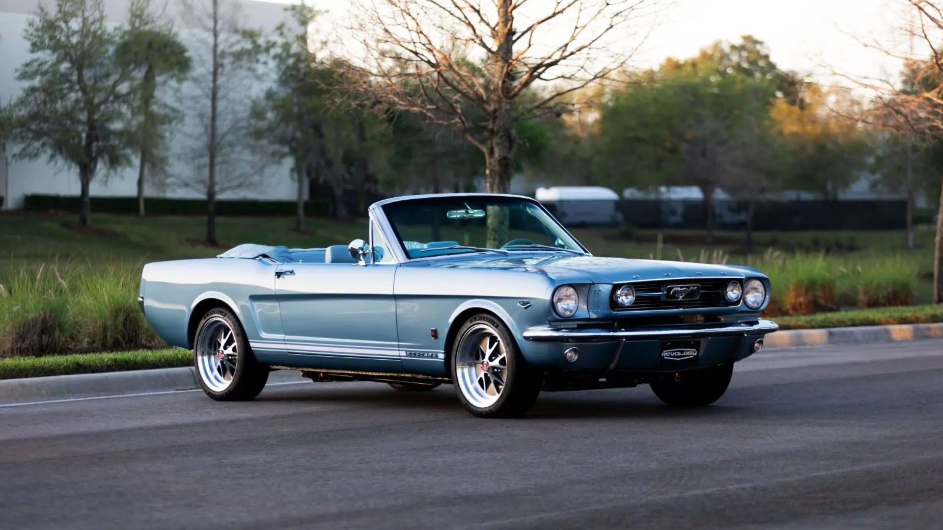 A lateral view of a light blue 1966 Mustang Convertible parked with open roof.