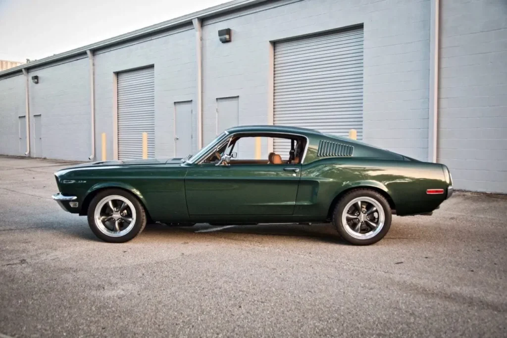 A side view of a 1968 Mustang GT 2+2 Fastback parked in front of a building