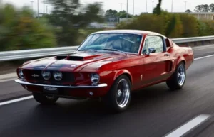 A man driving a 1967 Shelby GT 350 on a road