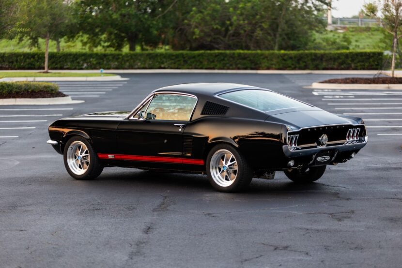 A lateral view of a black 1967 Mustang GT / GTA 2+2 Fastback parked in a parking lot.