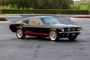 A rare view of a black 1967 Mustang GT / GTA 2+2 Fastback parked in a parking lot.