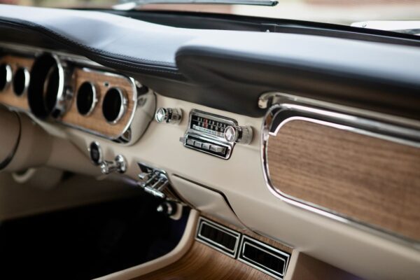 A close-up of a retro radio in a vintage 1966 Mustang Convertible.