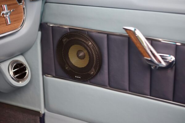 A close-up of a component speakers on a vintage 66 Mustang Convertible door.
