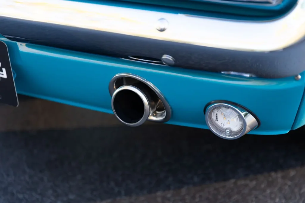 A close-up of a blue 1966 Mustang Convertible exhaust pipe.