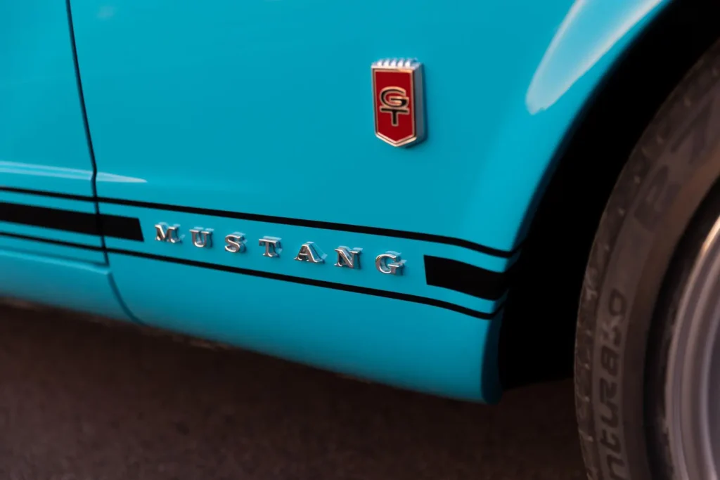 A close-up look of a blue 1966 Mustang Convertible letter emblem.