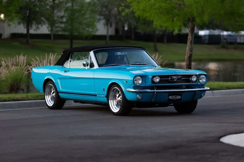 A lateral view of a blue 1966 Mustang Convertible with black stripe.