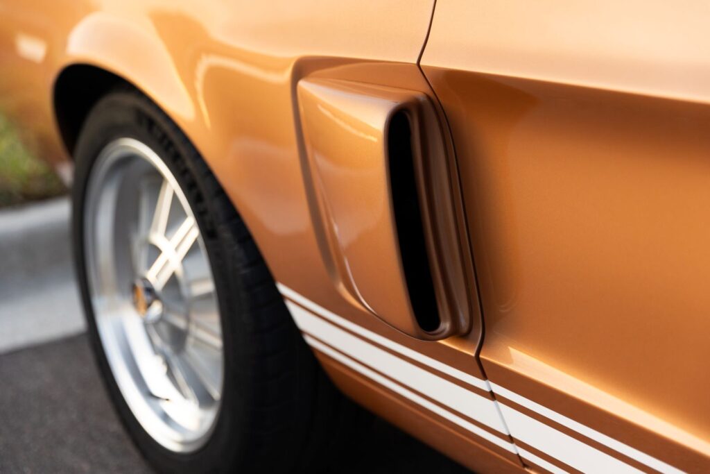 Close-up of the functional passenger-side quarter panel scoop and white G.T. 350 rocker stripes on a Copper metallic 1967 Revology Shelby GT350.