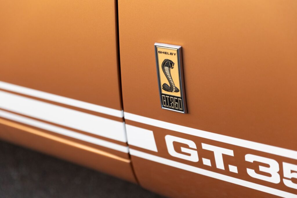 Close-up of the "Shelby G.T. 350" fender emblem and white rocker stripes on the Copper metallic body of a 1967 Revology Shelby GT350.