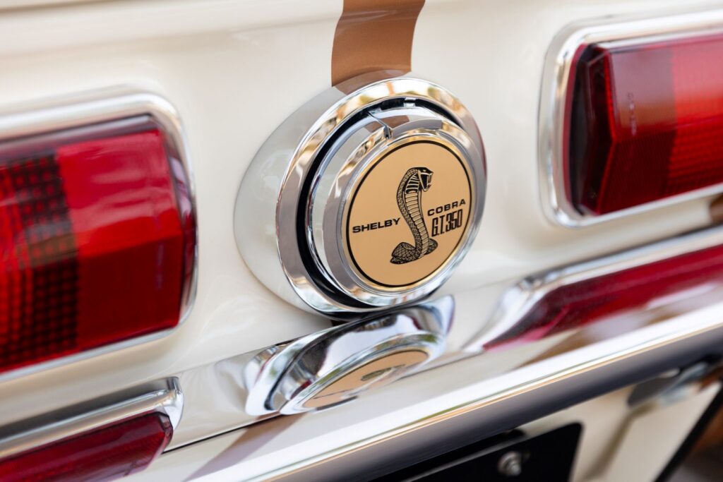 Close-up of the polished "Shelby Cobra G.T. 350" flip-down gas cap and chrome-trimmed taillights on a Copper metallic Revology 1967 Shelby.