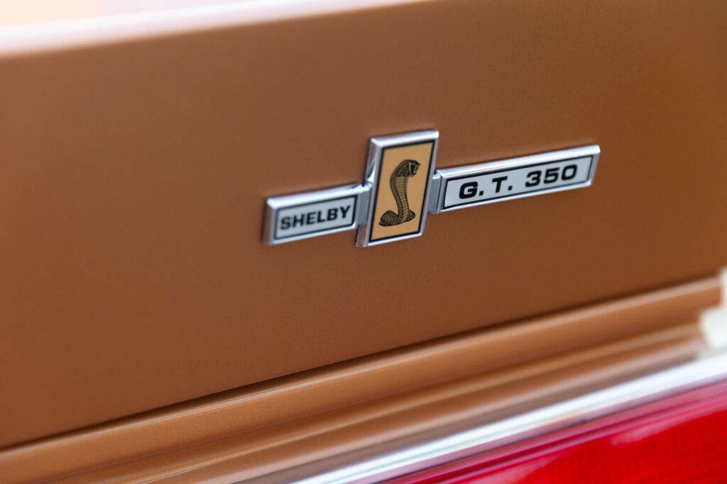 Extreme macro of the "Shelby G.T. 350" decklid emblem with the Cobra snake logo on the copper metallic rear spoiler of a 1967 Revology Shelby.