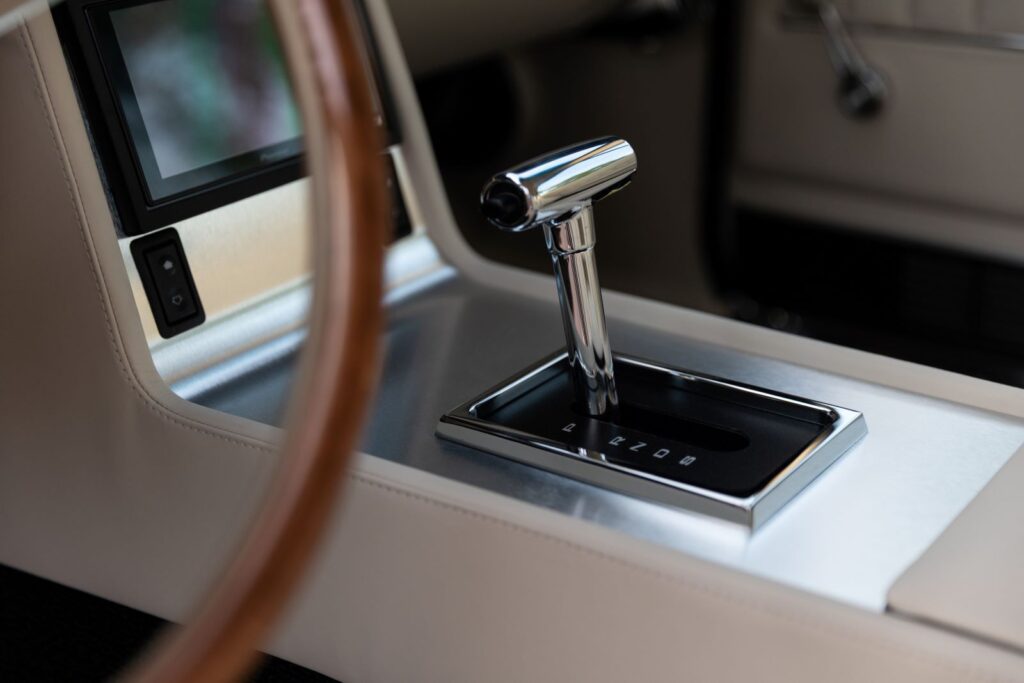 Close-up of a polished chrome T-handle automatic shifter on a custom leather-wrapped center console in a 1967 Revology Shelby GT350.