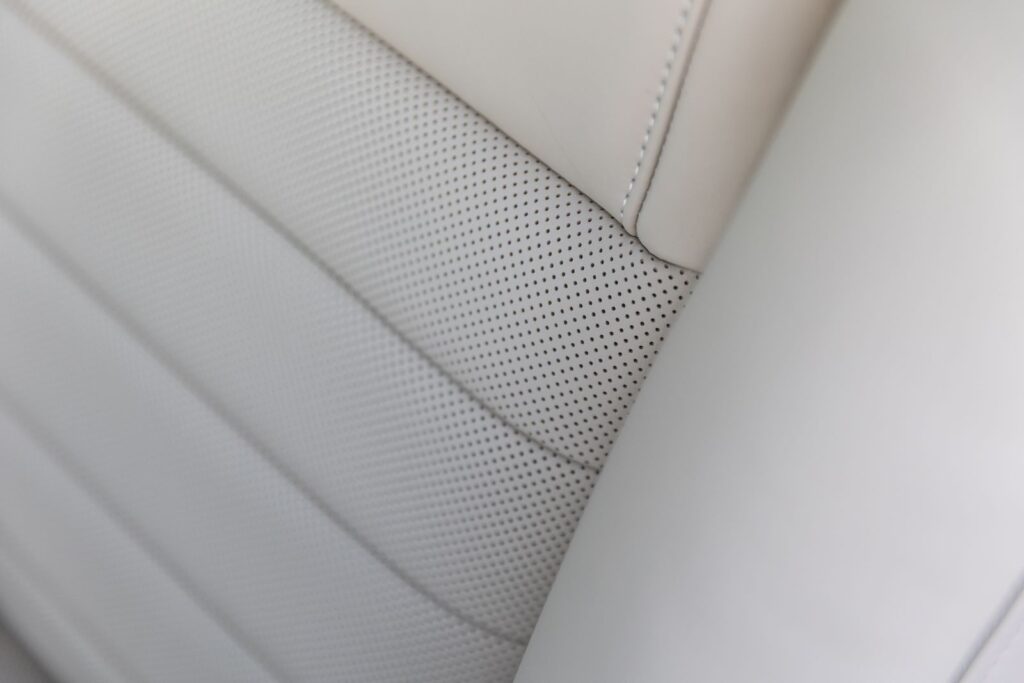 Close-up detail of perforated off-white leather seat upholstery with horizontal stitching on a 1967 Revology Shelby GT350.