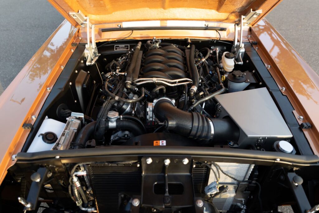 Engine bay view of a 1967 Revology Shelby GT350 featuring a modern 460hp Ford 5.0L Coyote V8 engine with a clean, OEM-style installation.
