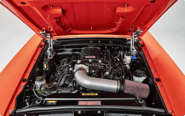 Supercharged Gen 4 5.0L Coyote V8 engine swap in a classic orange Ford Mustang restomod, featuring a Roush supercharger and high-flow cold air intake.