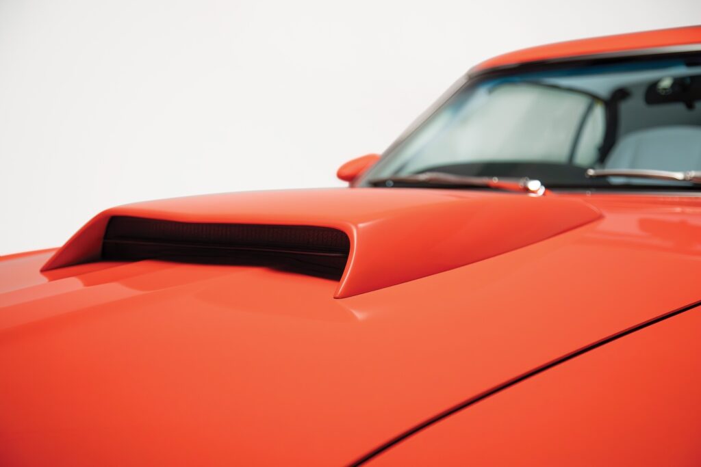 Close-up of the oversized functional hood scoop on an orange Revology 1969 Ford Mustang Boss 429, showcasing the seamless body-color integration and high-gloss paint finish.