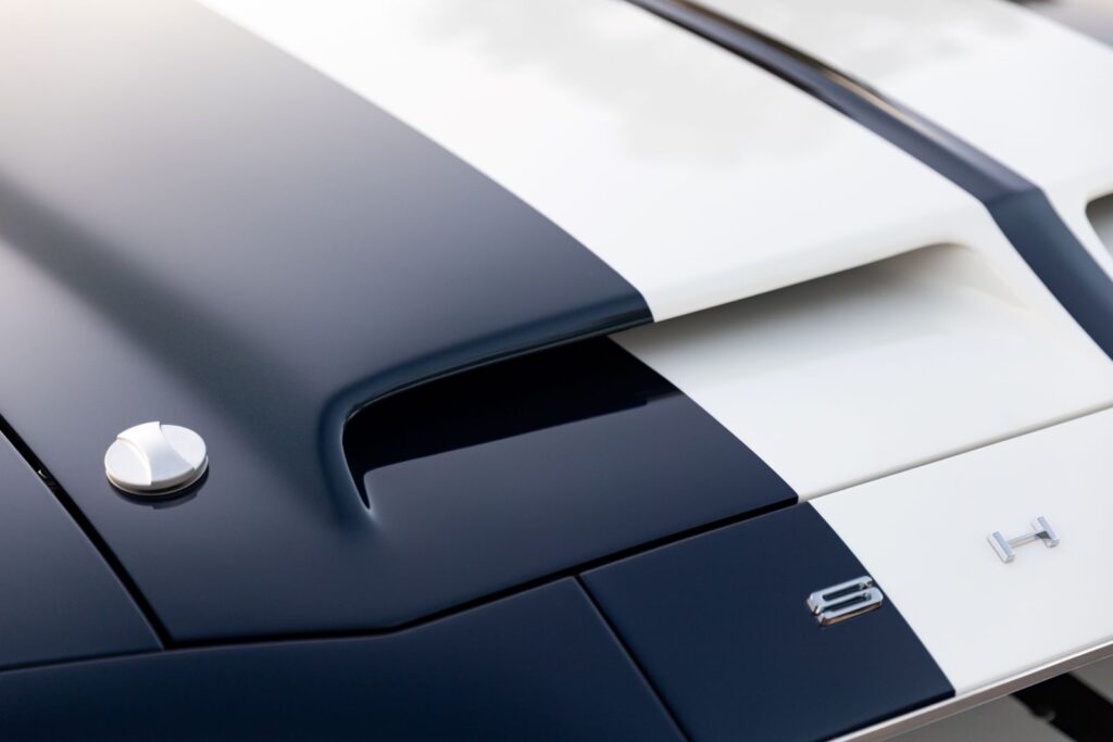 Macro side view of the functional ram-air intake scoop and polished hood pin on a dark green 1968 Revology Shelby GT500KR.