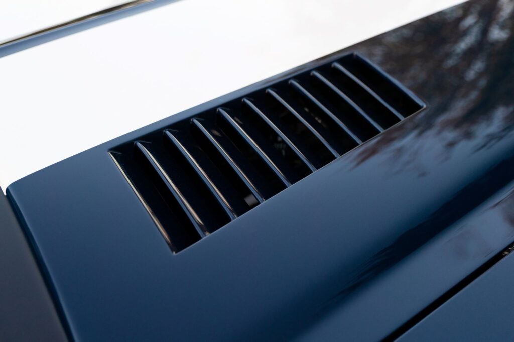 Close-up of the black louvers on the dark green hood of a 1968 Revology Shelby GT500KR, functioning as heat extractors for the engine bay.