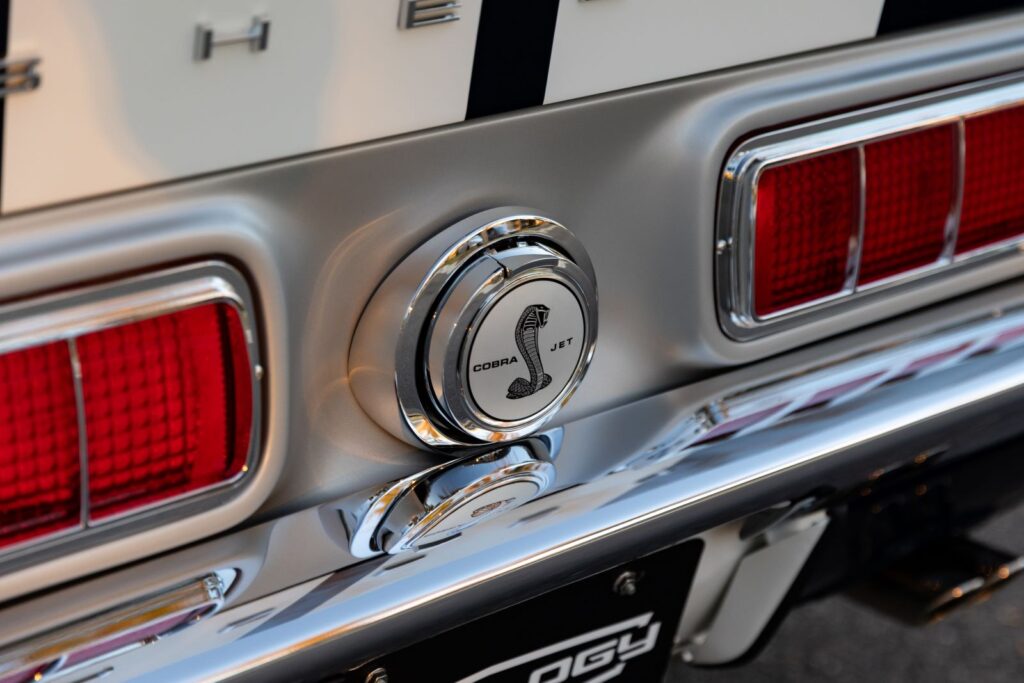 Macro view of the polished "Cobra Jet" flip-down gas cap and silver tail panel on a 1968 Revology Shelby GT500KR.
