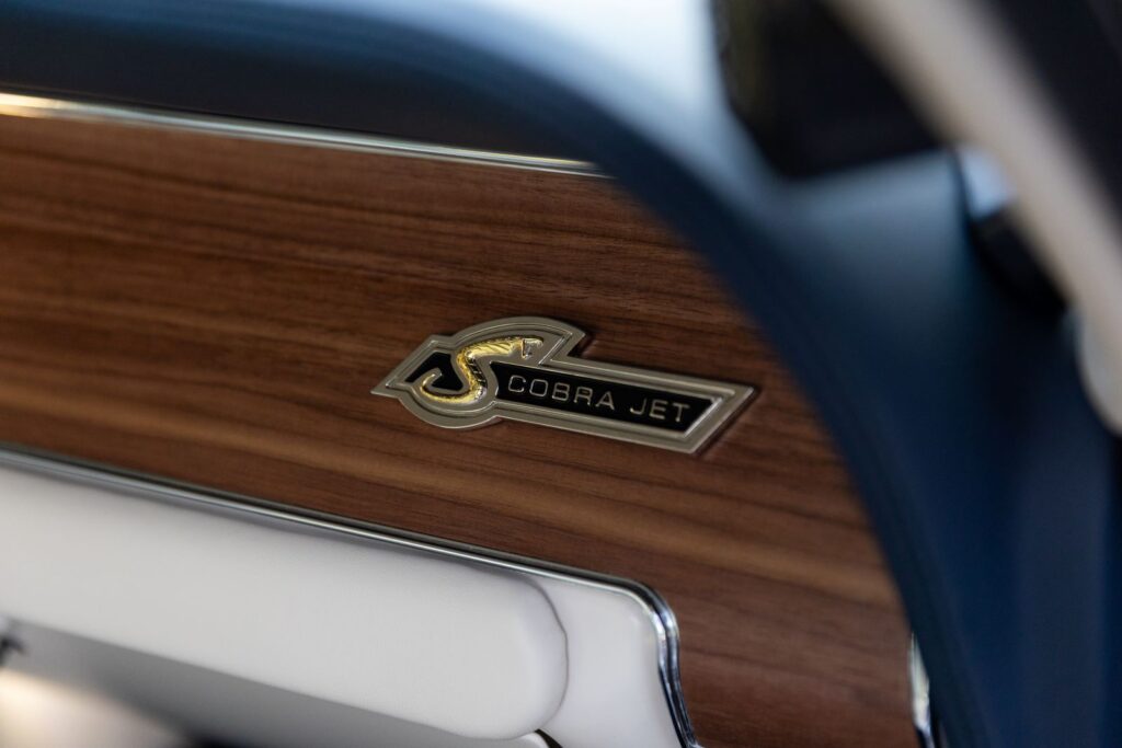 Extreme close-up of the "Shelby Cobra Jet" dash emblem mounted on a deluxe wood grain dashboard inside a 1968 Revology GT500KR.