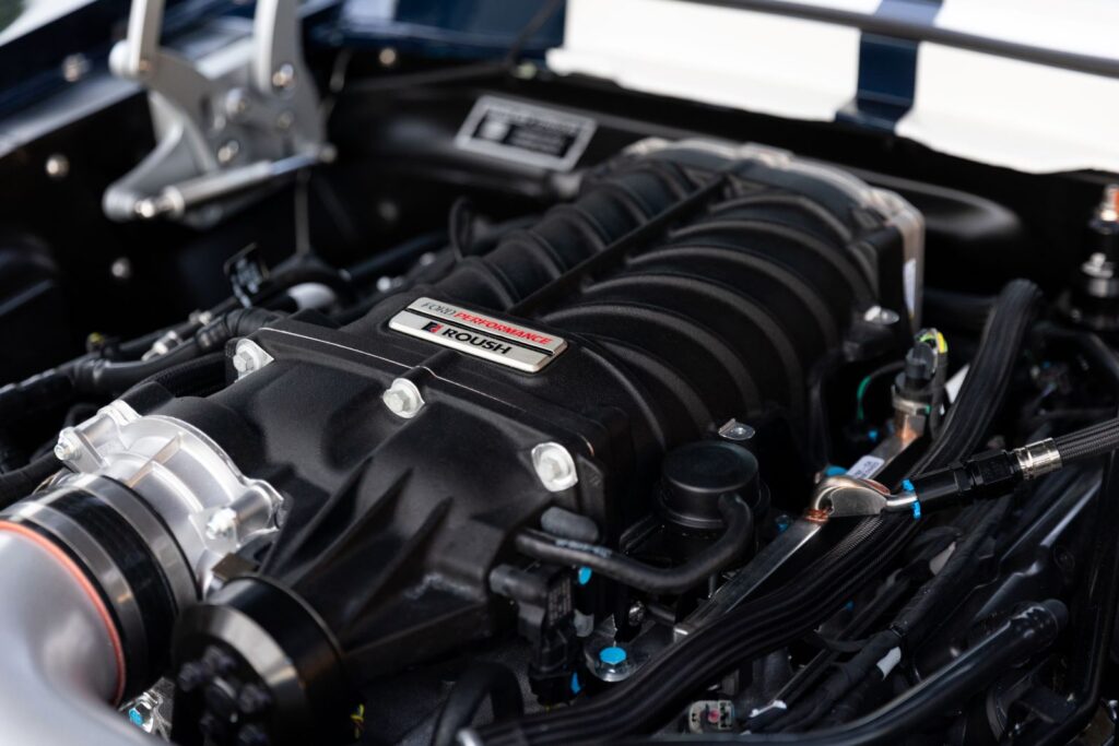 Close-up of a black Roush supercharger mounted on a 5.0L Coyote V8 engine inside a 1968 Revology Shelby GT500KR.