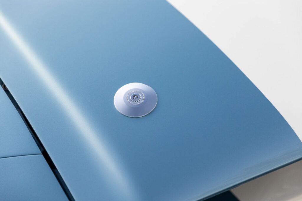 Close-up of a modern flush-mounted hood pin on the metallic blue hood of a 1967 Revology Shelby GT500.