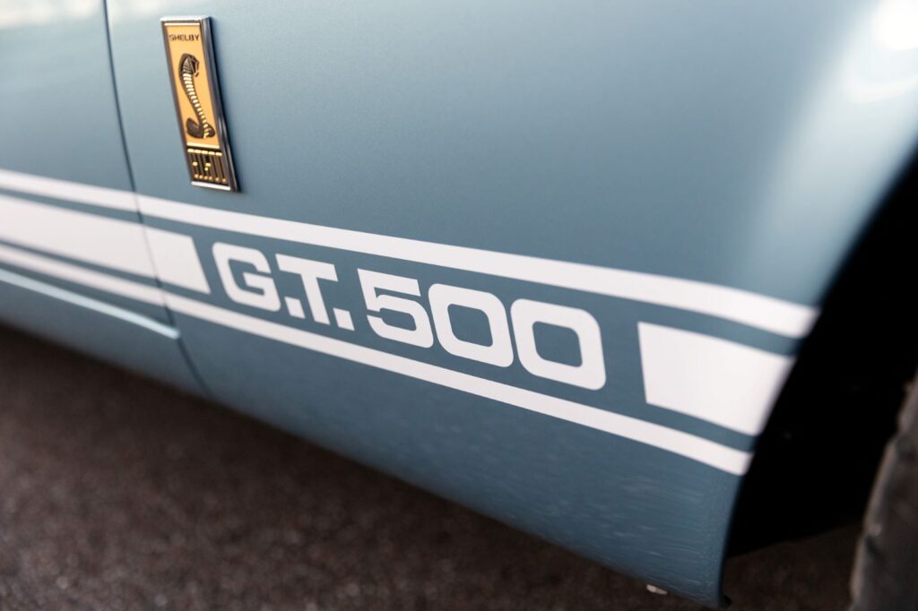 Close-up of the white G.T.500 rocker panel stripes on the lower side of a metallic blue 1967 Revology Shelby GT500 Fastback.