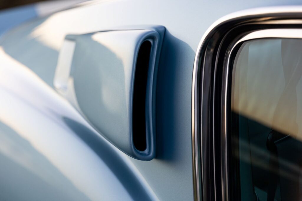 Close-up of the upper B-pillar air extractor scoop and chrome window trim on a metallic blue 1967 Revology Shelby GT500 Fastback.