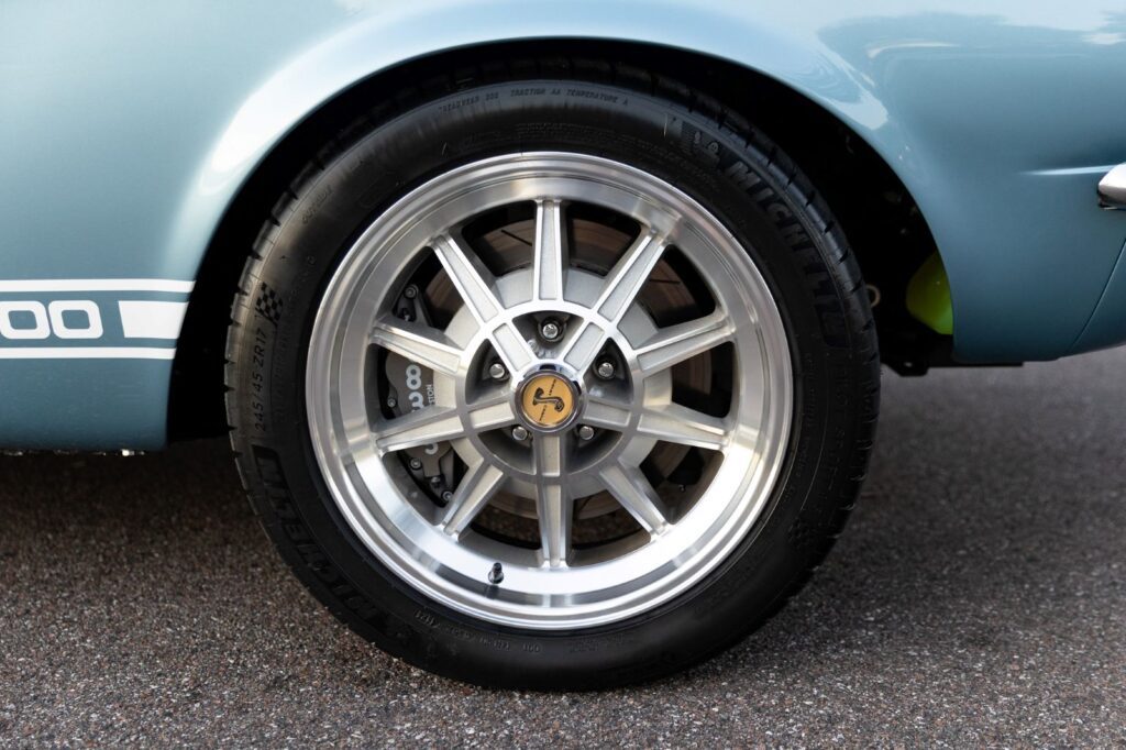 Close-up of a 10-spoke alloy wheel with a Shelby Cobra center cap and modern disc brakes on a 1967 Revology GT500 Fastback.