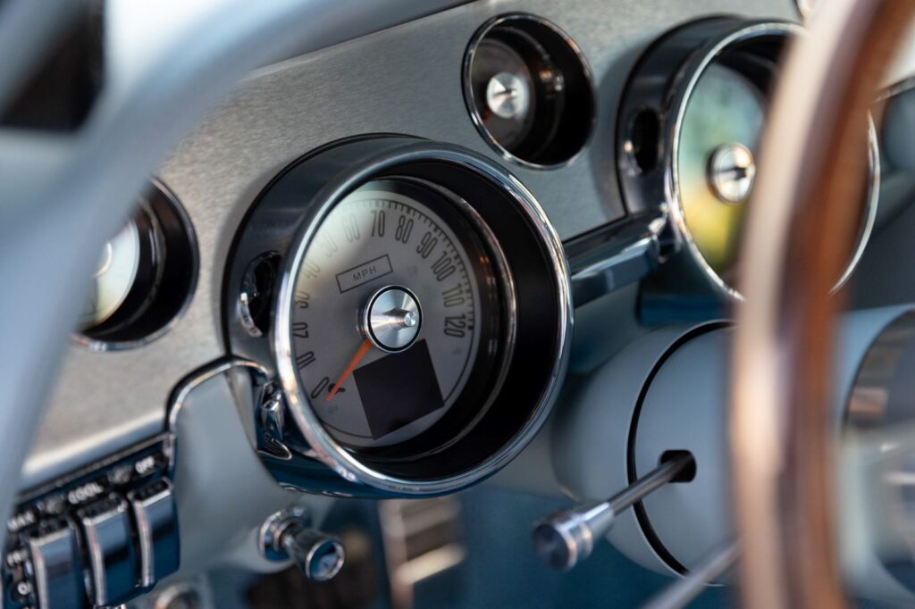 Close-up of the silver-faced electronic gauges and chrome toggle switches in a 1967 Revology Shelby GT500 dashboard.
