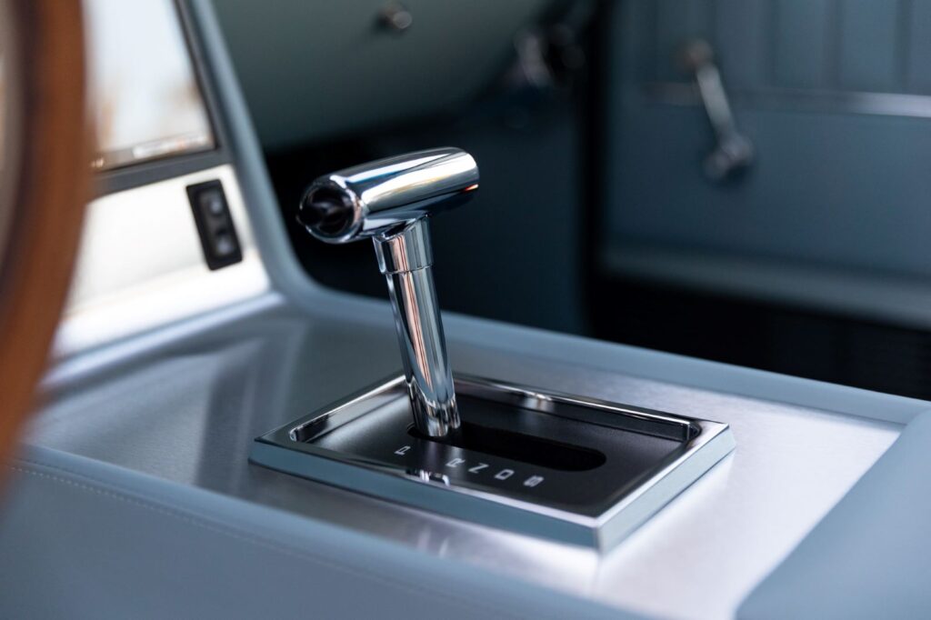 Close-up of a polished chrome T-handle automatic shifter on a custom leather-wrapped center console in a 1967 Revology Shelby GT500.