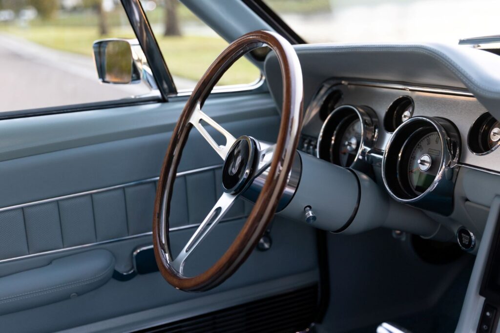 Profile view of the wood-rimmed steering wheel and leather-wrapped dashboard in a 1967 Revology Shelby GT500.